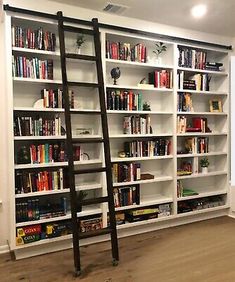 a ladder leaning up against a bookshelf in a room with white walls and wooden floors