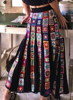 a woman standing in front of a mirror wearing a black top and multicolored skirt