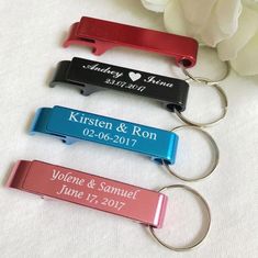 three personalized bottle openers sitting on top of a white table with flowers in the background