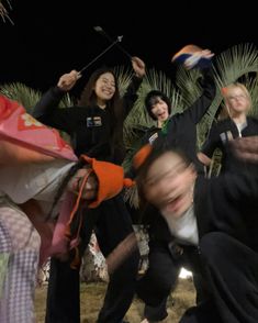 a group of people standing next to each other in front of a palm tree at night