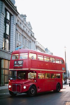 a red double decker bus driving down the street