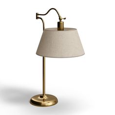 a lamp that is on top of a white surface with a gold base and a beige shade