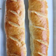 two long loafs of bread sitting on top of a white tray next to each other