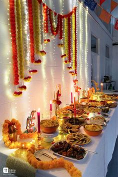 a long table filled with lots of food on top of a white cloth covered table