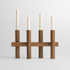 four candles are placed in front of each other on a wooden stand with white candles