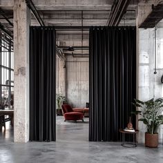 an industrial style office with black curtains and red chairs in the middle of the room