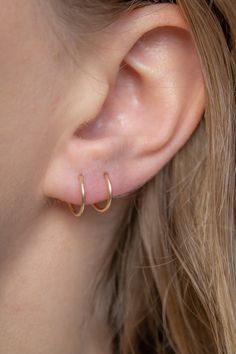 a close up of a woman's ear wearing gold hoop earrings