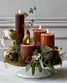 a white plate topped with lots of candles and greenery on top of a table