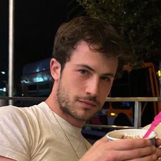 a man holding a bowl of food and looking at his cell phone in front of him