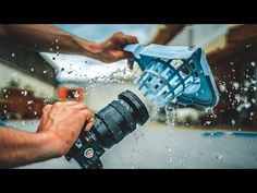 a person is holding a camera and spraying water on the ground with their hands while another person holds an object in front of them