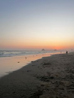 people are walking on the beach at sunset