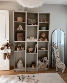 a baby's room with stuffed animals and toys on the floor in front of a white bookcase