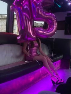 a woman sitting on top of a couch in front of a giant number 25 balloon