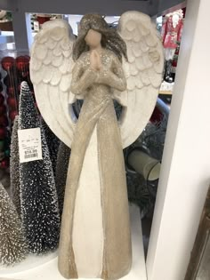 an angel figurine sitting on top of a shelf next to other christmas trees