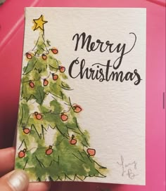 someone holding up a christmas card with a tree on it