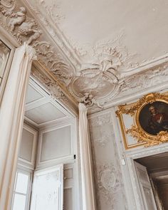 an ornately decorated room with white walls and gold trim on the ceiling, along with paintings