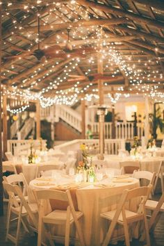 tables and chairs are set up for an event with string lights strung over the ceiling