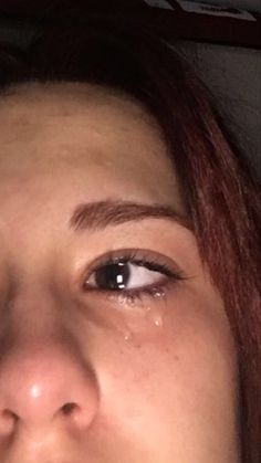 a close up of a woman's face with tears on her eyes and nose