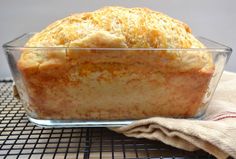 a loaf of bread sitting in a glass dish on top of a wire cooling rack