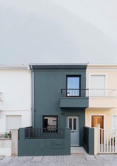 two houses with balconies on the second and third floors are painted in different colors