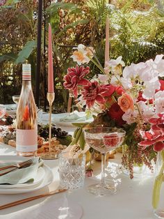 the table is set with flowers, wine glasses and plates for an elegant dinner party