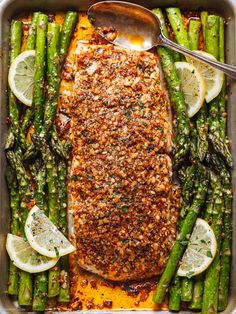 salmon and asparagus in a pan with lemon wedges