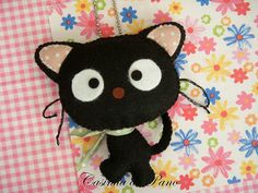 a black cat with big eyes on a pink and white checkered table cloth background