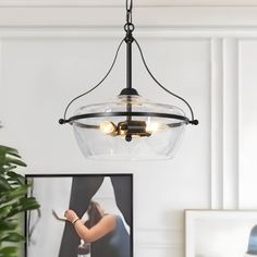 a glass light fixture hanging from the ceiling above a table with a framed photo on it