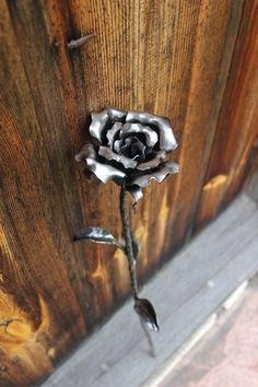 a metal rose on the side of a wooden door with nails sticking out of it