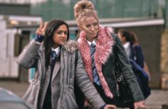 two girls walking down the street with one pointing up