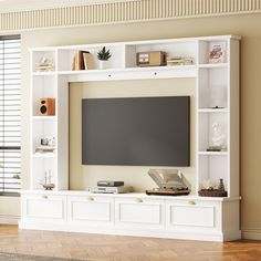 a white entertainment center with bookshelves and a flat screen tv mounted on the wall