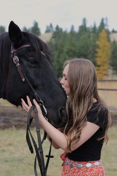 a girl is petting the nose of a horse