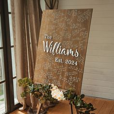 a wooden sign sitting on top of a table next to two vases filled with flowers