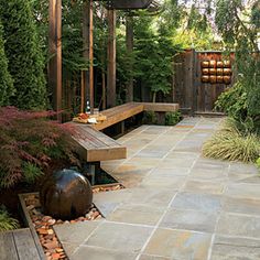 an outdoor patio with benches and plants in the back ground, surrounded by greenery