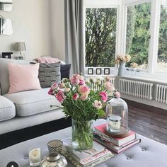 a living room filled with lots of furniture and flowers in a vase on top of a coffee table