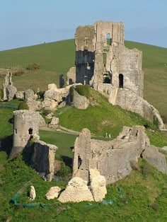 an old castle sits on top of a grassy hill in the middle of nowhere,