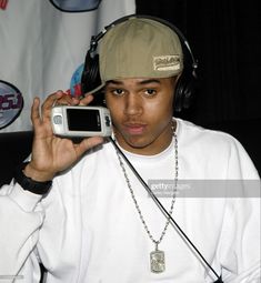 a young man wearing headphones and listening to music on his cell phone in front of a microphone