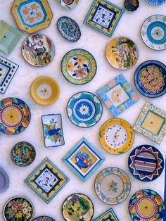 many colorful plates are arranged on a white tablecloth with blue and yellow trimmings