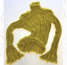 a green knitted sweater laying on top of a white surface