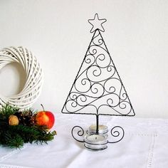 a wire christmas tree on a table next to some fruit