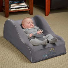 a baby laying on top of a gray chair