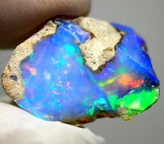 a hand holding a piece of opal in it's left hand, with the other