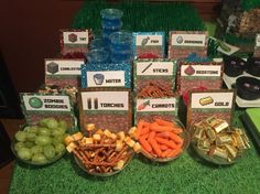 a table topped with lots of snacks and water bottles on top of green carpeted flooring