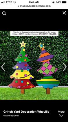 three brightly colored christmas trees in the grass