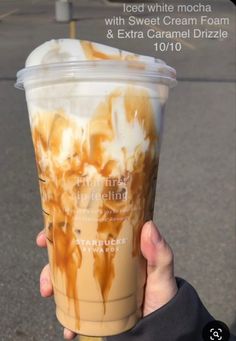 someone holding up a cup of ice cream and caramel drizzle on the street