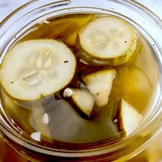 a jar filled with liquid and sliced up cucumber slices in the bottom half