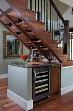 a kitchen with an island and wine rack under the stairs