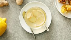 a cup of tea with lemon slices and ginger on the side