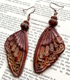 a pair of earrings sitting on top of an open book