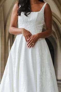 a woman in a white wedding dress is posing for the camera with her hands on her hips